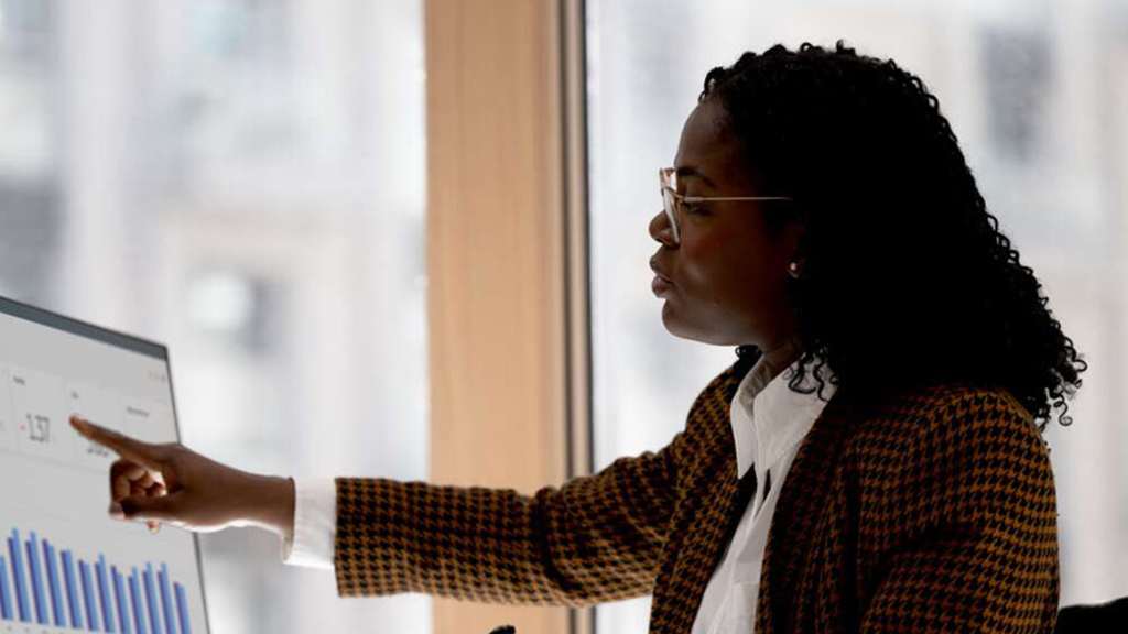 Bank manager pointing at financial charts on a computer screen during a client meeting.